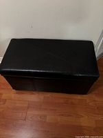 Closed black faux leather storage ottoman, top view