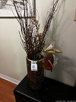Vase with faux stems and nearby tall black reed bundle