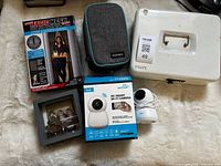 Group shot of all five items: Magic Mesh box, Ozchin pouch, SAFE cash box, Travel Fund bank, iTeck camera box and device