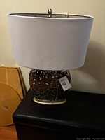 Full view of lamp with shade, finial, base and cord visible