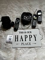 Three cordless handsets, answering-machine base, charging cradle, power cords displayed on surface