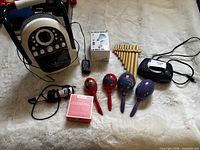 Group shot showing all items laid out on surface: karaoke unit, microphone, adapter, Sonix speaker box, LED bulb box, pan flute, maracas, CD clock radio