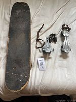 Top view of worn skateboard deck, pair of metal clip-on skates beside it