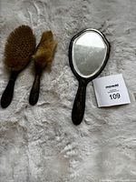 Full view of hand mirror, large brush, small brush
