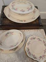Stack of salad plates, open serving bowl, covered tureen on oval underplate