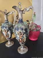 Two ornate Italian decanters with cherub relief