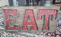 Front view of wood sign showing EAT letters and LED bulbs
