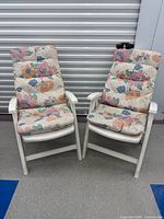 Front view of both white plastic garden chairs with floral cushions
