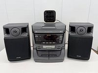 Front view of complete Sharp stereo system with two speakers and Sony clock radio placed on top
