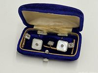 open blue velvet case showing pair of cufflinks and three shirt studs