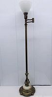 Full view of brass and onyx torchiere floor lamp with milk glass shade