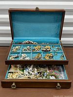 Open jewelry box showing velvet lined compartments filled with assorted jewelry