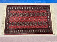 Full view of red Bokhara rug showing overall design and fringe