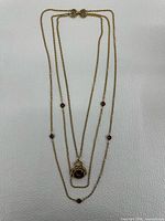 Full view of triple strand necklace showing chain layout, stones, and pendant