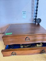 closed wooden chest with drawer ajar showing silverware