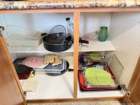 overview of cabinet contents showing cookware, racks, plastic bins and glass bottle