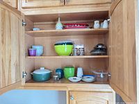 Cabinet view showing most items including mixing bowls, casserole, tumblers, steamer inserts, shakers, funnel, containers, plates