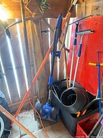 Overview showing Snow Joe electric snow shovel, rakes, shovels, squeegees, extension cord, storage tub, hose