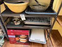 Full shelf view showing ceramic bowl, glass dishes, enamel pan, sheet pans, oven rack box