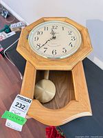 Full view of wall clock showing dial, case, pendulum, and size tag