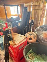 Assorted garden supplies including crates, bin, soccer planter, stakes