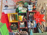 Overall view of stacked crates with potting mixes, fertilizers, hand tools, cinder block and pinwheel