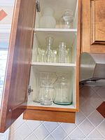 Cabinet view showing three shelves filled with clear glass vases
