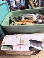 Tote with assorted hand tools and boxed landscape edging visible