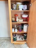 Full view of cupboard showing four shelves of assorted kitchenware