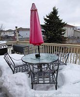Patio set on deck in winter snow showing table, chairs and umbrella
