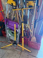 Two yellow tripod-mounted corded work lights alongside folding chair and shop tools