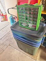 Stack of plastic totes with green drawer organizer displayed on top