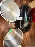 Black electric roaster oven base with lid, stainless shallow pot/bowl, stainless lid visible