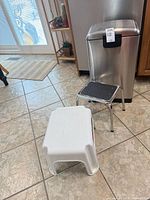 Group shot of Rubbermaid plastic step stool, chrome step stool and stainless steel trash can