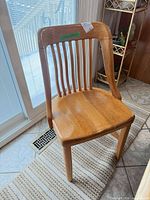 Front view of one oak slat-back chair showing design and finish