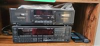 Sony dual cassette deck stacked above Kenwood receiver with remotes visible