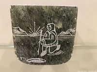 Front view showing incised Inuit hunter scene and signature
