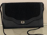 Front view showing pleated flap, gold-tone accent and braided strap