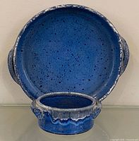 Front view of large round dish and smaller bowl showing cobalt blue speckled glaze and drip rim