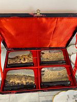 Open brocade case showing four viewing stones in red padded interior