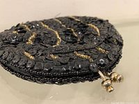 Front view of black sequin clutch showing gold bead stripes and clasp