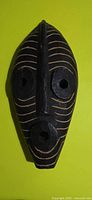 Front view of carved wooden mask showing overall shape and groove pattern