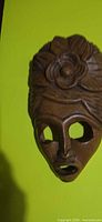 Front view of carved wooden mask on green background