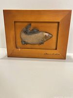 Frontal view of framed carved fish showing signature