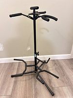 Full view of black metal guitar stand showing three lower cradle arms and two upper padded hangers