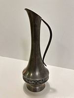 Side view of tall pewter pitcher showing handle, neck, and decorative band