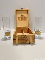 Two whisky glasses and open wooden box showing interior divider and branding