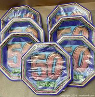 Six of the seven packs of paper plates showing design and sealed wrap