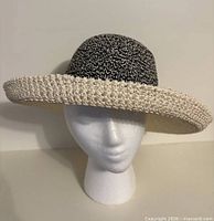 Front view of beige brim and black crown straw hat on stand