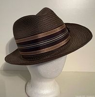 Front left view of brown woven fedora with striped ribbon band on mannequin head